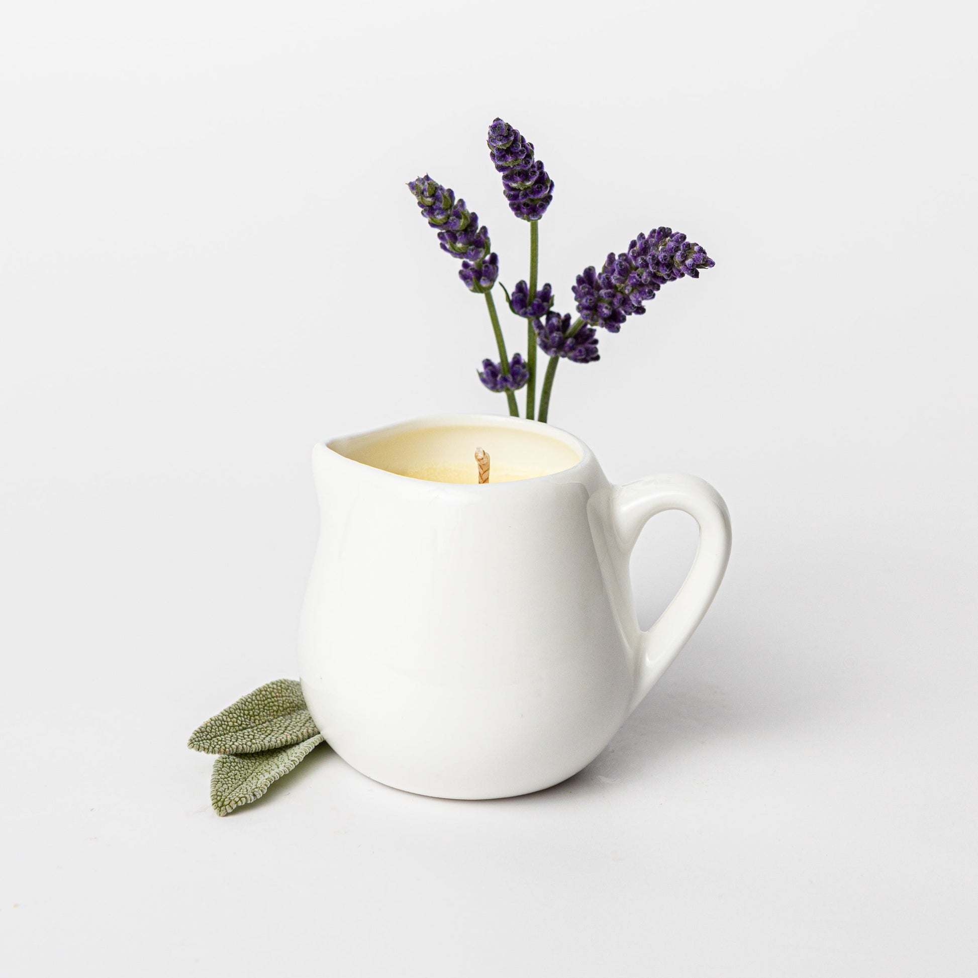 White mug with a lit candle and lavender flowers on a light background